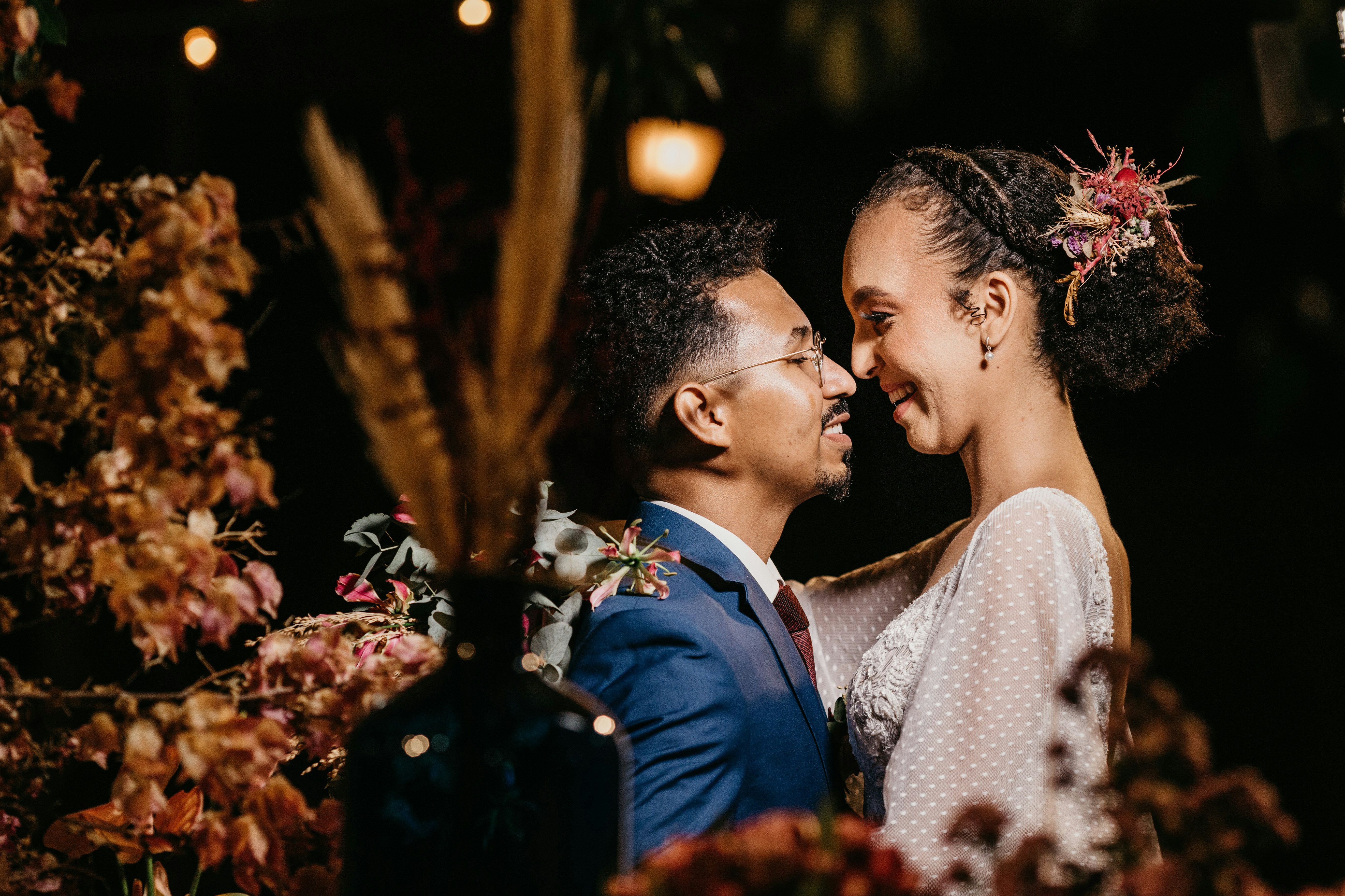 man in blue suit kissing woman in white floral dress